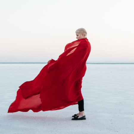 Woman Standing salt flats with fabric wrapped around her and blowing in the wind.